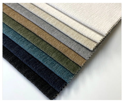 A stack of Revolution Performance Fabrics upholstery swatches in neutral and bold colors, displaying the wide range of color options for furniture upholstery.